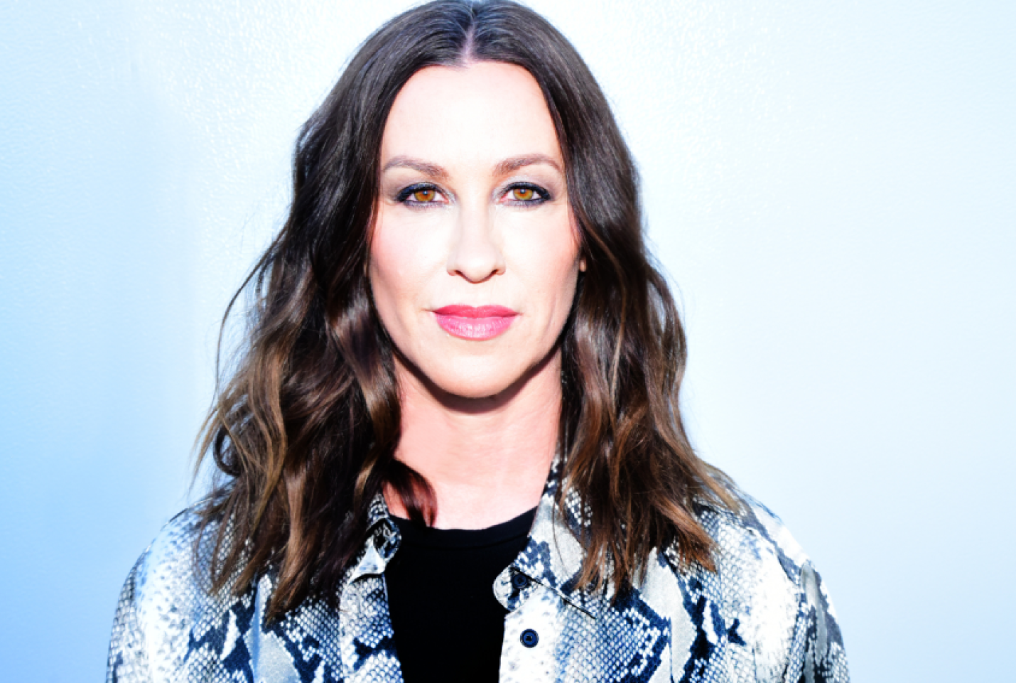 Alanis Morissette is smiling.
